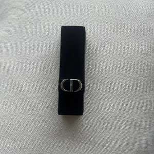 Rouge Dior läppstift 200 Nude Touch - Säljer ett Rouge Dior läppstift i färgen 200 Nude Touch. Snyggt beige-nude nyans med matt finish. Lyxigt svart hylsa med silverdetaljer och CD-logga. Perfekt för dig som gillar naturliga toner och elegant design.