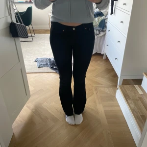 Svarta bootcut jeans - Säljer ett par svarta bootcut jeans från Gina tricot med rå kant nertill. Jeansen har klassisk femficksdesign och stängs med knapp och dragkedja. Snygg passform som sitter tajt upptill och släpper ut vid benslutet.