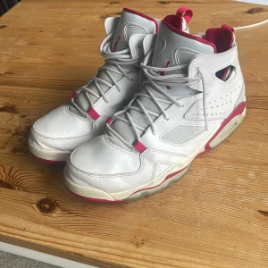 Vita och röda Nike Air Jordans - Säljer ett par vita och röda Nike Air Jordans med högt skaft och klassisk design. Skorna har grå snörning, rund tå och detaljer i rött längs sula och insida. Perfekta för dig som gillar streetwear och sneakers med retrostil.