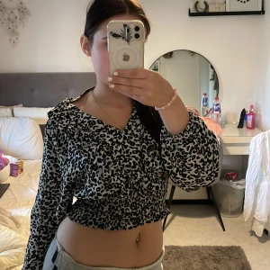 blus från Amelie & Me - Säljer en svartvit blus från Amelie & Me med leopardmönster. Blusen har långa ärmar, v-ringning och smockad midja som ger en snygg passform. Perfekt för någon i storlek M eller S. kontakta mig om pris❤️