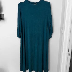 Blå långklänning från Lindex - En enkel och stilren blå långklänning från Lindex med rund halsringning och långa ärmar. Tillverkad i ett mjukt och lätt material som ger en avslappnad passform. Perfekt för dig som gillar minimalistisk stil.