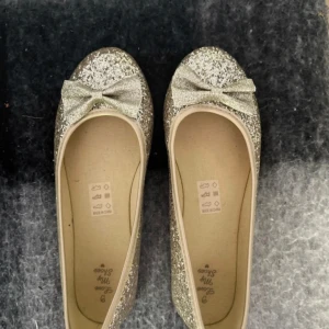 Ballerinaskor  - Säljer dessa glittriga ballerinaskor med en söt rosett framtill. Superfina till både vardag och fest!