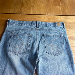 Bootcut ljusblå jeans från MNG Jeans - Ljusblå lågmidjade bootcut jeans från MNG Jeans med klassisk femficksdesign och snygga broderade detaljer på bakfickorna. På lappen står det 38 (tror jag lite svårt att läsa - se sista bilden) men skulle själv säja att de är 36.