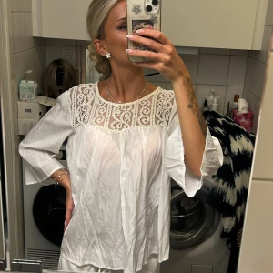 Vit blus med spets - Säljer en vit blus med vackra spetsdetaljer upptill och vida trekvartsärmar.  Perfekt för en gullig skoloutfit med ett par jeans eller kostymbyxor!