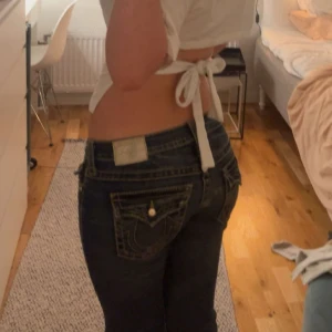 True Religion jeans med blingdetaljer - Pris går att diskutera. Dem är knappast använda.Säljer ett par mörkblå True Religion jeans med ikoniska kontrastsömmar och stora bakfickor med broderad logga. Jeansen har snygga blingknappar och nitar framtill som ger extra edge. Modellen är lågmidjad och har en bootcut fit. Inga defekter