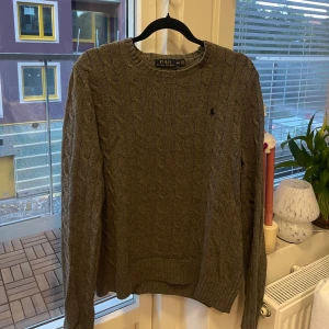 Ralph Lauren Tröja (M) - Säljer en grå kabelstickad tröja från Polo Ralph Lauren. Sparsamt använd. Storlek M