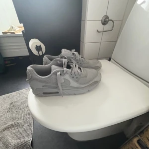 Grå Nike Air Max sneakers - Säljer ett par helgrå Nike Air Max sneakers med klassisk siluett och synlig luftbubbla i sulan. Skorna har mesh och syntetmaterial i ovandelen, snörning och en chunky sula som ger skön dämpning. Perfekta för dig som gillar stilrena och sportiga sneakers. 