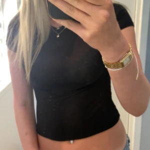 Svart tight topp från H&M Divided - Svart, tunn och tight topp från H&M Divided. Modellen är kortärmad och har en klassisk rund halsringning. Toppen är enkel och stilren, perfekt att matcha med jeans eller kjol. Materialet är lätt och stretchigt för en bekväm passform.