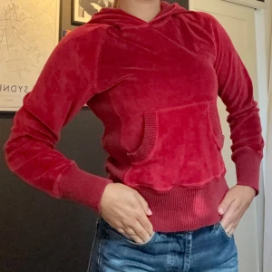 Röd velourhoodie med huva - Mysig röd hoodie i mjuk velour med huva och magficka. Tröjan har långa ärmar, breda ribbade muddar🍓