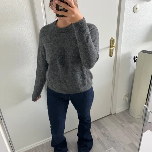 Grå stickad tröja från Zara - Mysig grå stickad tröja från Zara med rund hals och ribbade muddar. Tröjan har en loose passform och långa ärmar, perfekt för att hålla dig varm under kyliga dagar. Enkel och stilren design som funkar till allt