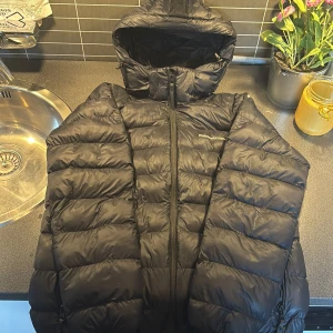 Svart pufferjacka Peak Performance - En svart peak performecs jacka med ett litet hål på höger arm och vänstra dragkedjan är sönder men arnas e den i bra skick