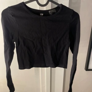 Svart ribbad croppad topp H&M Sport - Svart långärmad croppad topp från H&M Sport. Toppen är ribbad och har en tight passform, superskön i storlek S, men passar även för XS🤍