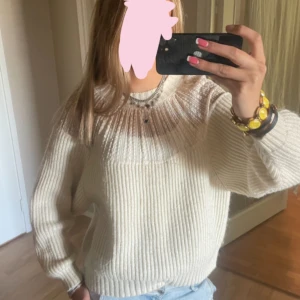 Vit stickad tröja med spetsdetalj - Superfin vit stickad tröja med breda ribbor och transparent spets upptill vid axlar och halsringning. Långärmad och lite loose fit, perfekt att styla med jeans för en chill look. Snygg och mysig, passar dig som gillar ljusa och fräscha vibes.
