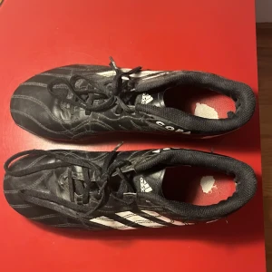 Adidas Copa svarta fotbollsskor - Klassiska Adidas Copa fotbollsskor i svart skinn med vita ränder och snörning. Skorna har rund tå och dobbar för bra grepp på planen. Perfekta för dig som vill ha en tidlös och stilren look på fotbollsplanen. 