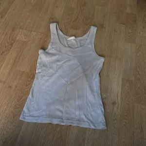 Ljusblå ribbad linnetopp Gina Tricot - Säljer en ljusblå ribbad linnetopp från Gina Tricot, basically basics-kollektionen. Toppen är ärmlös med klassisk rund halsringning och stretchigt material som sitter snyggt på kroppen. Perfekt att styla med jeans eller kjol för en enkel look.