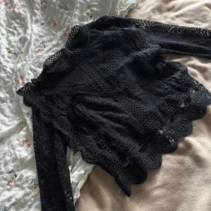 Svart spetsblus med volangdetaljer - Köpt på vinted så jag vet tyvärr inte vart den är ifrån 🖤 Supersnygg svart blus i spets med lång ärm och höga volangdetaljer längs kanterna. Blusen har en hög hals och vackra broderade mönster som ger en lyxig känsla.