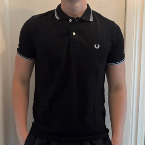 Svart Fred Perry piké med vit kant - Vanlig svart fred perry piké. Tröjan är helt ny. Säljer även ut andra saker från min gaderob så kolla gärna min sida och se om du hittar något du gillar!