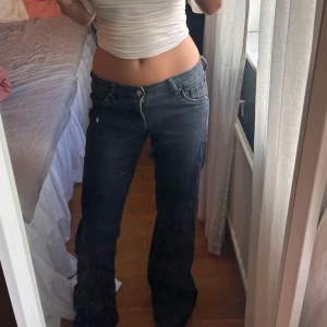 Svarta bootcut jeans låg midja - Säljer ett par svarta jeans med bootcut-modell och låg midja. Jeansen har klassisk femficksdesign och är tillverkade i ett mjukt denimtyg. Perfekta för dig som gillar en avslappnad och trendig look.