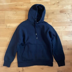 Svart hoodie från Selected Homme - Stilren svart hoodietröja från Selected Homme. Tjock i materielet och värmer bra. Väldigt skön och mysig när det är kyligt. Storlek: S.
