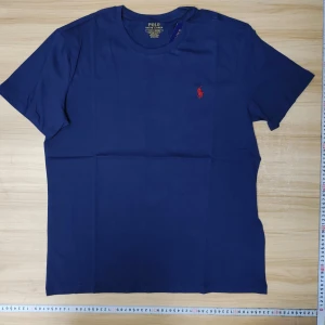 Polo Ralph Lauren T-shirt - Helt ny, snygg blå t-shirt från Polo Ralph Lauren med röd broderad logga på bröstet. Modellen är custom slim fit och har rund halsringning samt korta ärmar. Perfekt för en stilren och klassisk look. Säljer för att den är för stor för mig.
