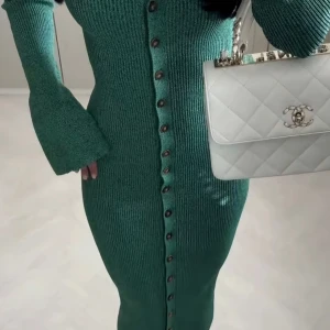 Grön lång stickad klänning från Adoore - Snygg grön lång stickad klänning från Adoore med v-ringning och knappar hela vägen framtill. Klänningen har långa trumpetärmar och en figurnära passform som ger en cool siluett. Perfekt för dig som gillar stilrena detaljer och stickat.