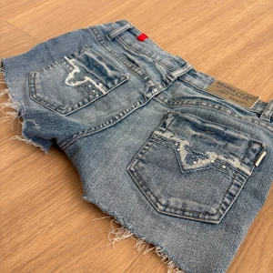 Blå jeansshorts från Miss Natalie - Snygga blå jeansshorts från Miss Natalie. De har råa, fransiga kanter och slitningar på bakfickorna med coola detaljer. Dom passar mig som är storlek 36, iggnorera storlek 42. Perfekta för varma dagar och chill stil. Däremot finns det ingen KNAPP på byxorna så dom stängs inte/kan fixa om det verkligen behövs! Skriv om ni funderar över ngt ❤️😋