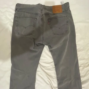 Grå Levi's 501 jeans W34 L32 - Säljer ett par grå Levi's 501 jeans med klassisk rak passform och knappgylf. Jeansen har fem fickor, snygga sömmar och den ikoniska läderpatchen bak i midjan. Perfekta för dig som gillar en tidlös look med streetkänsla. Pris kan diskuteras, de bara att höra av sig.