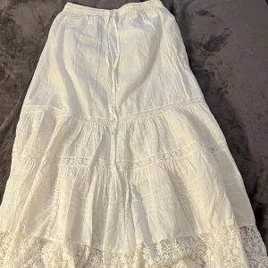 Vit långkjol med spets från Coline - Supersöt vit långkjol från Coline, köpt i Frankrike! Kjolen har volanger och fina spetsdetaljer längst ner💕 Aldrig använd 