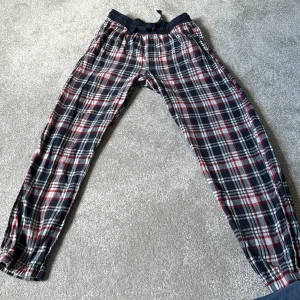 Rutig mjukisbyxa från Kappahl - Mysiga mjukisbyxor från Kappahl i röd, blå och vit rutig design. Byxorna har resår och snörning i midjan samt resår vid bensluten. Perfekta för chill dagar hemma eller som pyjamasbyxa.