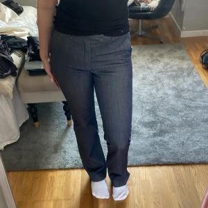 Mörkblå kostymbyxor från Filippa K - Snygga mörkblå kostymbyxor från Filippa K i rak modell. Byxorna har klassiska fickor fram, en passpoalficka bak och hällor för bälte. Materialet är mjukt och har en jeansliknande känsla men med dressad look. Perfekta för en clean och stilren outfit.