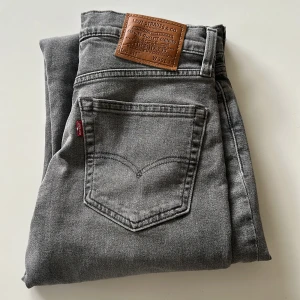 Grå Levi's 511 jeans straight fit - Snygga grå jeans från Levi's modell 511 med klassisk femficksdesign och läderpatch bak. Jeansen har en rak passform och är tillverkade i mjukt denimtyg. Perfekta för dig som gillar en clean och stilren look.