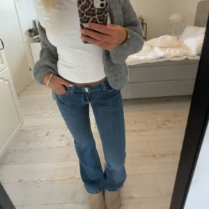 Blå bootcut jeans med broderad ficka - Snygga blå jeans med bootcut passform och låg midja. Perfekta för dig som gillar en tidlös look.💃 Sparaamt använda! Sitter bra på mig som är 169