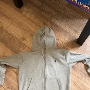 Ralph Lauren Zip Hoodie - En grå zip hoodie från Ralph Lauren i mycket gott skick, pris kan diskuteras. säljes endast då jag tänkte prova en annan stil.