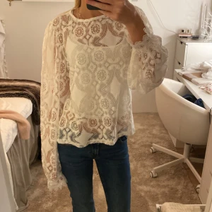 Vit spetsblus med puffärmar - Superfin vit blus i spets med unikt broderat mönster och transparenta detaljer. Blusen har långa puffärmar med spetskant vid ärmslut och rund halsringning. Perfekt för dig som gillar romantisk och trendig stil. Passar mig som vanligtvis har XS/S