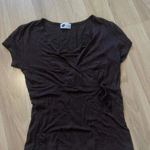 Svart omlottopp från Orsay - Svart omlottopp från Orsay med v-ringning och knyt i sidan. Toppen har korta ärmar och är figurnära i modellen. Perfekt att styla med jeans eller kjol för en snygg look.