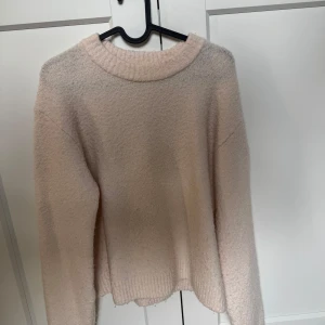 Ljusrosa stickad tröja från H&M - Supermjuk och fluffig ljusrosa stickad tröja från H&M. Tröjan har en rund halsringning, ribbade muddar och lång ärm. Perfekt för lager-på-lager och chill höst- eller vinterstil.