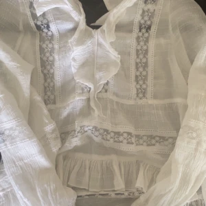 Vit ”Volang” blus  - Vit volang blus . Jätte gullig tröja som svänger ut lite ner till men är figursydd upptill . Med broderat Blommigt mönster. 