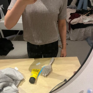 Beige ribbad kortärmad tröja - Säljer en beige ribbad tröja med korta ärmar och rak passform. Tröjan har en enkel och stilren look med diskreta vertikala ränder i materialet. Perfekt till jeans eller kjol för en chill och snygg outfit.