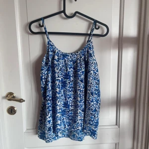 Blåvit mönstrad linnetopp 157 - Supersöt linnetopp från 157 i storlek S med blått och vitt abstrakt mönster. Tunt och luftigt material, perfekta smala axelband och avslappnad passform. Perfekt för varma dagar när du vill ha något lätt och snyggt.