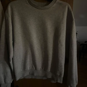 Grå basic sweatshirt i bomull - Enkel och stilren grå sweatshirt med rund hals och långa ärmar. Perfekt för en chill och avslappnad look. Tröjan har ribbade muddar vid ärmslut och nederkant. Passar dig som gillar minimalistisk stil.