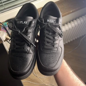 Svarta sneakers från Replay - Stilrena svarta sneakers från Replay med klassisk siluett och snygga detaljer. Skorna har snörning, rund tå och är tillverkade i strukturerat syntetmaterial med Replay-logga på plösen och sidan. Perfekta för dig som gillar en clean och urban look. Kommer med låda bara skriva för mer bilder skorna är i väldigt bra skick det är bara att tvätta sidorna lite och efter det är dom 10 av 10 