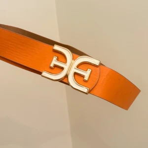 Orange bälte - Snyggt orange bälte  med ett stort, guldigt BB-spänne framtill. Perfekt accessoar för att lyfta en outfit. Storlek M-L