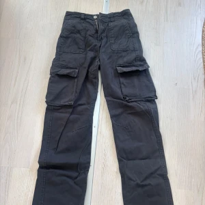 Svarta cargopants från Stradivarius - Svarta cargopants från Stradivarius med flera stora fickor på benen och bak. Byxorna har inte använts på länge men är i väldigt bra skick och lätta att stylea. 