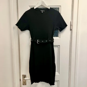 Svart ribbad klänning Missguided - Svart klänning med bälte i midjan från Missguided. Använd max 2ggr så säljes i toppskick. Storlek 34 men passar även 36.