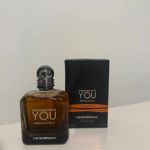 Emporio Armani Stronger With You Absolutely - Emporio Armani Stronger With You Absolutely är en parfym i en stilren, fyrkantig glasflaska med mörkbrun ton och silverfärgad rund kork. Medföljer gör en svart kartong med orange detaljer. Flaskan rymmer 100 ml och har en modern, lyxig känsla.