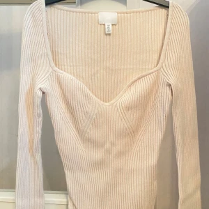 Ribbad ljusbeige topp från H&M - Supersnygg ribbad topp från H&M i ljusbeige. Långärmad och figurnära passform, perfekt att styla med jeans eller kjol. Mjuk och stretchig känsla.