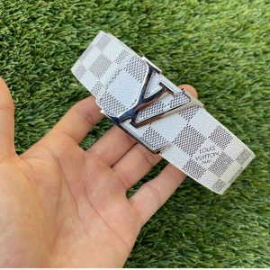 Vit rutig skärp bälte  - Snyggt bälte i vitt med grått rutmönster och stor silverfärgad logga som spänne. Bältet är gjort i skinn och har klassisk design med exklusiv känsla. Perfekt accessoar för att lyfta din outfit med en lyxig touch. Den är 110cm