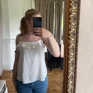 Vit topp med volang - Vit topp med volang vid bröstet. Storlek 42 men funkar äcen bra för de som normalt har mindre storlekar (jag har normalt S i tröjor). Säljer då den inte kommer till användning, knappt använd så i nyskick. Hör av dig om du har frågor, pris går att diskutera🫶