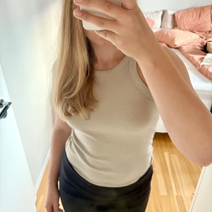 Beige ribbad linnetopp - Beige ribbad linnetopp med rund halsringning och breda axelband. Köpt från h&m i storlek M. Materialet är mjukt och stretchigt för en bekväm känsla hela dagen. Bra skick!🤗