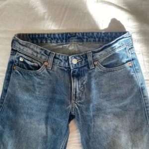 Lågmidjade jeans - Lågmidjade blå jeans med rak passform storlek W25 (XS). Märket är weekday och är i modellen Arrow Low. Jeansen har en lätt tvättad look som ger dem en vintagekänsla.
